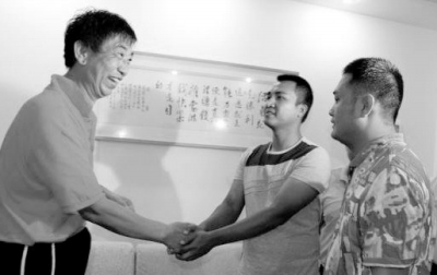      毕国昌（左）与涉事城管队员握手。网络图片