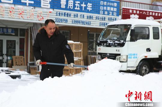 商户清扫门前及腰深的积雪。 李姗姗 摄
