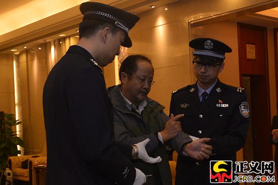 　在逮捕决定书上签完字，裴健强拉起袖子，准备接受公安干警给其带上手铐。钟波 摄