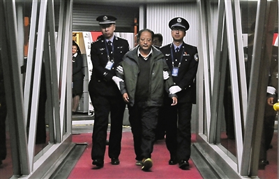 昨日，外逃6年的“百名红通”10号嫌犯裴健强被抓获归案。图为裴健强（中）被执法人员带离北京首都国际机场。新华社发