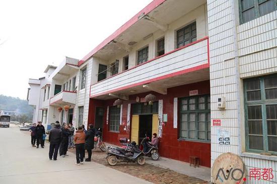 犯罪嫌疑人聂露勇的老家，村民在门口围观。门前，默默静坐的是他86岁的老奶奶。