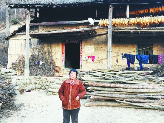 一个尘肺病人的妻子站在自家门前